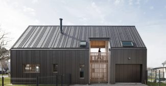 Maison contemporaine à bardage métallique noir, vue de face, illustrant un projet de construction sur un terrain agricole.