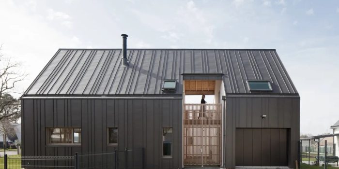 Maison contemporaine à bardage métallique noir, vue de face, illustrant un projet de construction sur un terrain agricole.