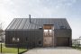 Maison contemporaine à bardage métallique noir, vue de face, illustrant un projet de construction sur un terrain agricole.