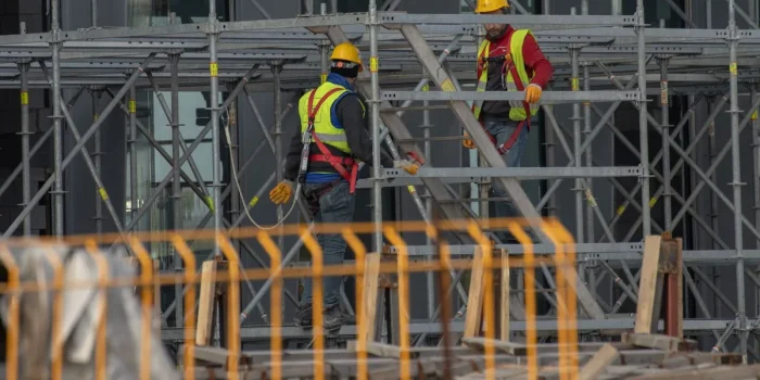 Équipe de construction en tenue de sécurité vérifiant les équipements et discutant des risques sur un chantier