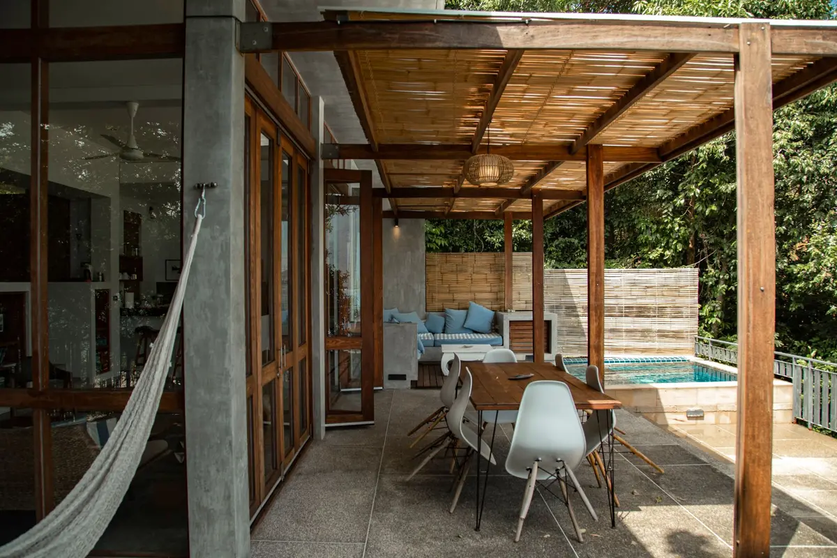 Terrasse tropicale protégée par pergola en bois et brise-soleil naturels