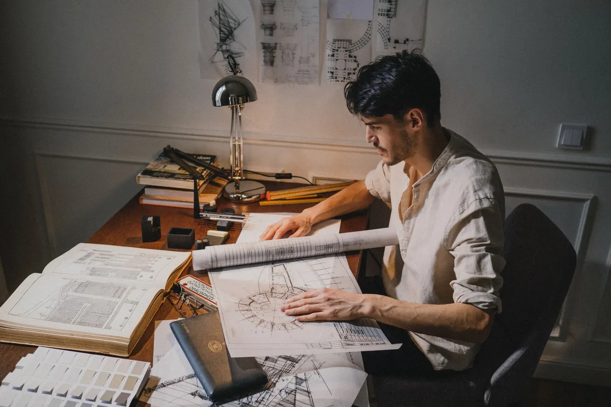 Professionnel du bâtiment consultant des plans et listes de références sur son bureau