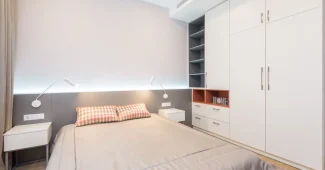 Petit meuble de rangement avec tiroirs et penderie dans une chambre aux tons clairs