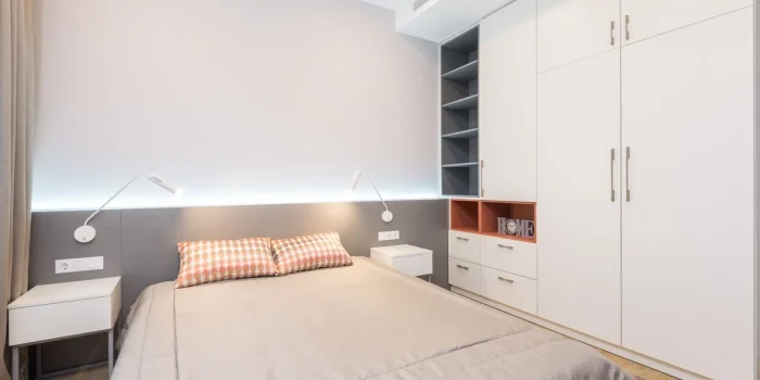Petit meuble de rangement avec tiroirs et penderie dans une chambre aux tons clairs