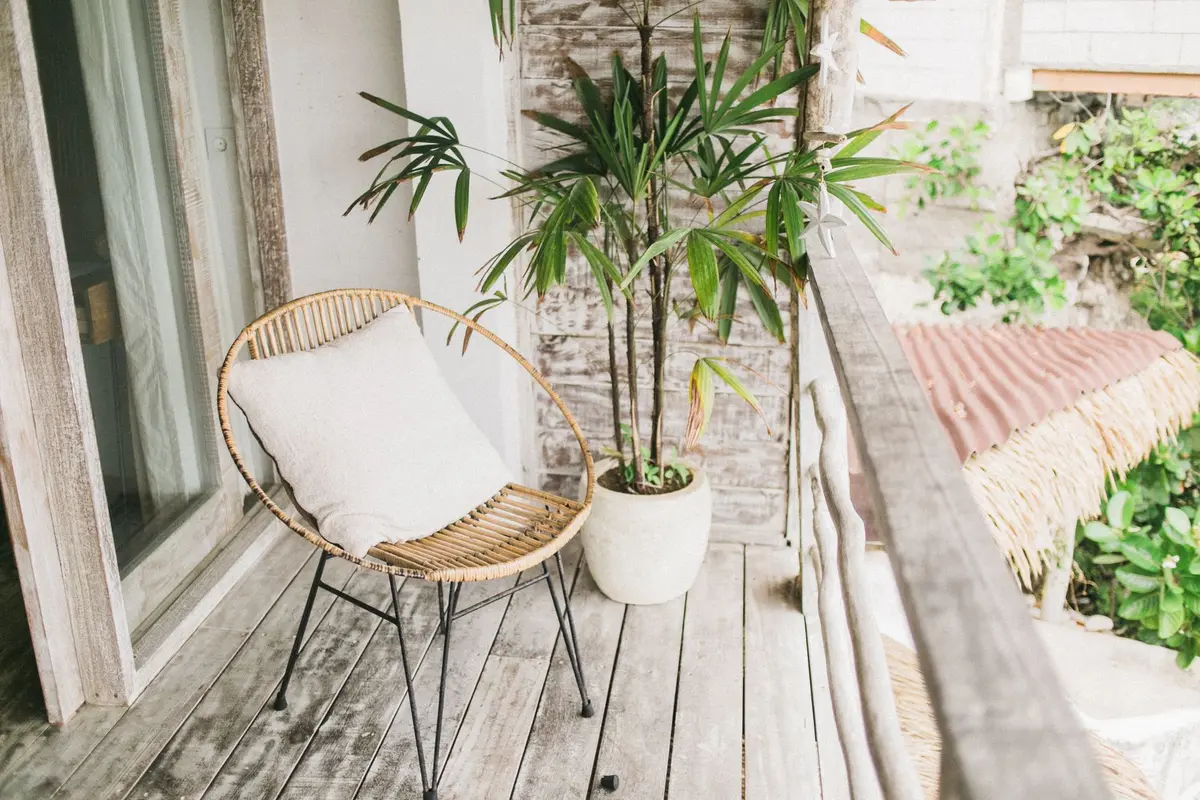 Détail d'une terrasse avec coussins colorés, tapis extérieur et pots de fleurs
