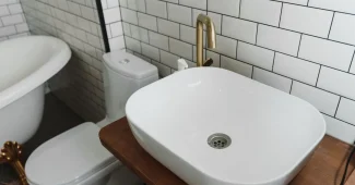 Cuvette de toilettes avec dépôts de calcaire blanc et jaune, main gantée tenant une brosse