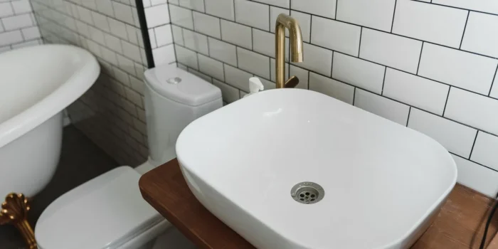 Cuvette de toilettes avec dépôts de calcaire blanc et jaune, main gantée tenant une brosse