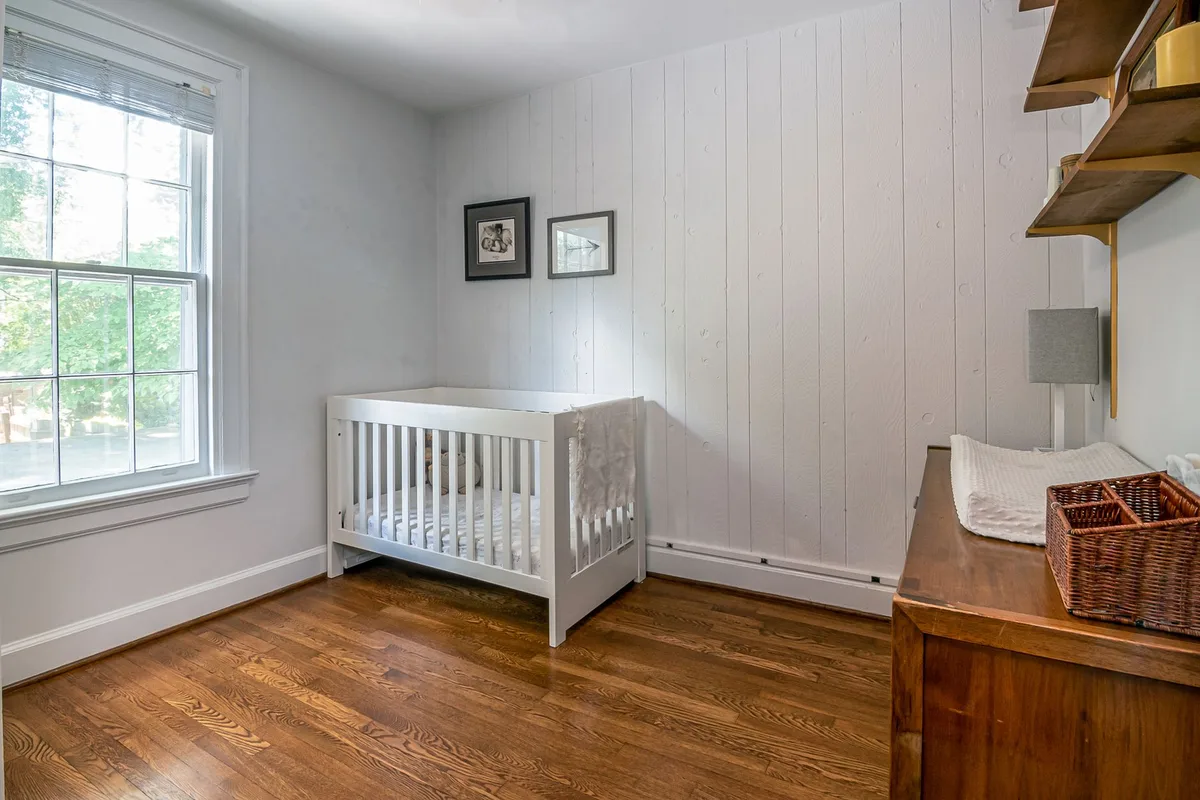 Chambre de bébé aménagée avec un lit conforme, une commode avec plan à langer et des rangements fermés organisés.
