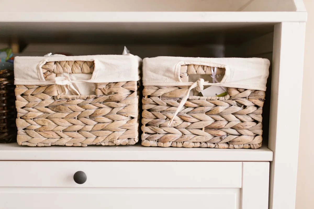 Boîtes et paniers de rangement bien organisés dans une chambre de bébé pour classer couches et produits par fréquence d'