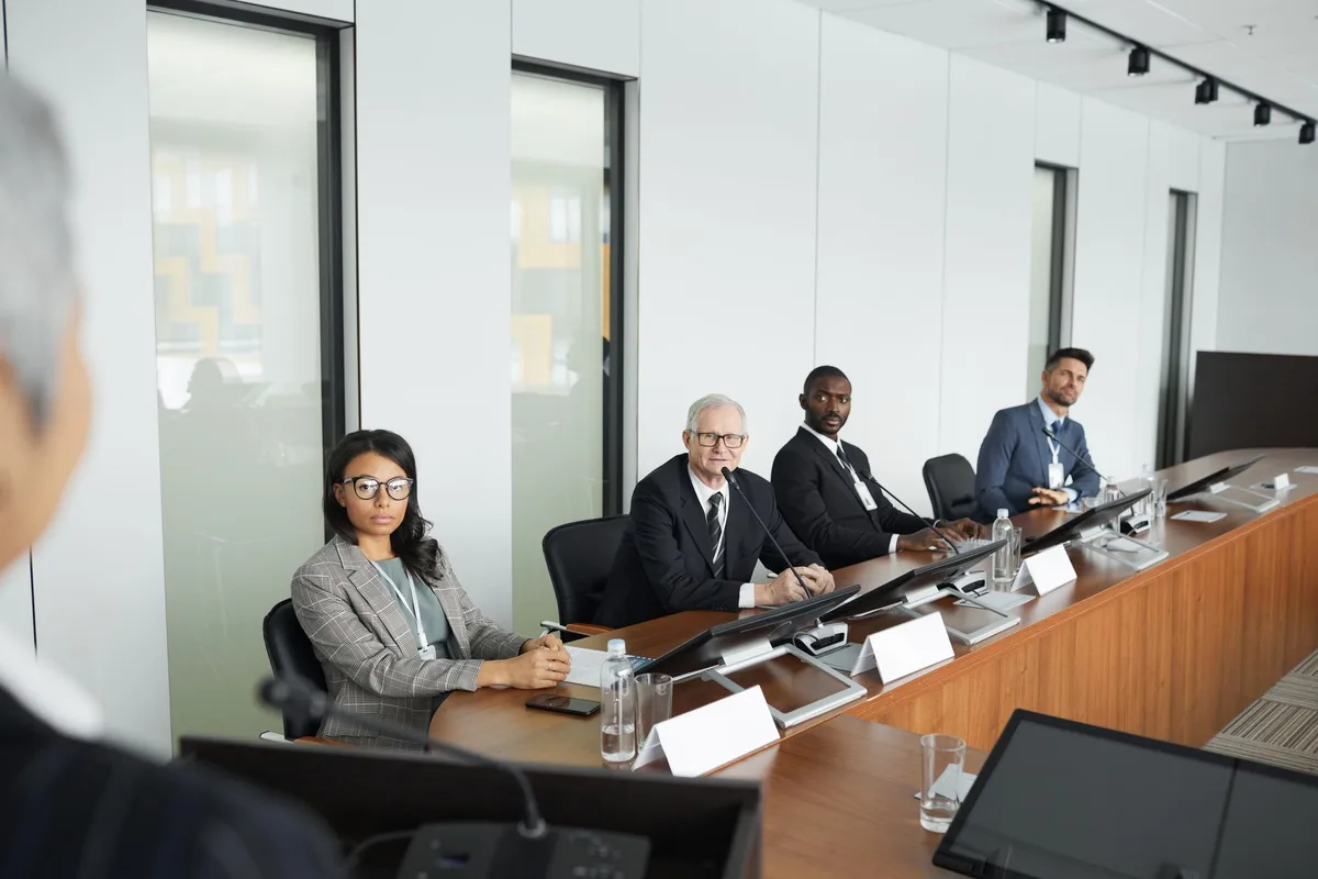 Réunion avec différents types de participants écoutant une présentation adaptée à leur rôle
