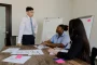 Personne présentant un projet structuré à des collègues autour d'une table avec schémas et notes