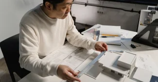Main d'architecte esquissant des plans sur papier dans un éclairage studio doux