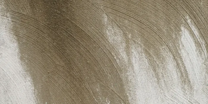 Intérieur minéral avec mur en pierre brute, sol en béton poli et jeux de lumière soulignant les textures