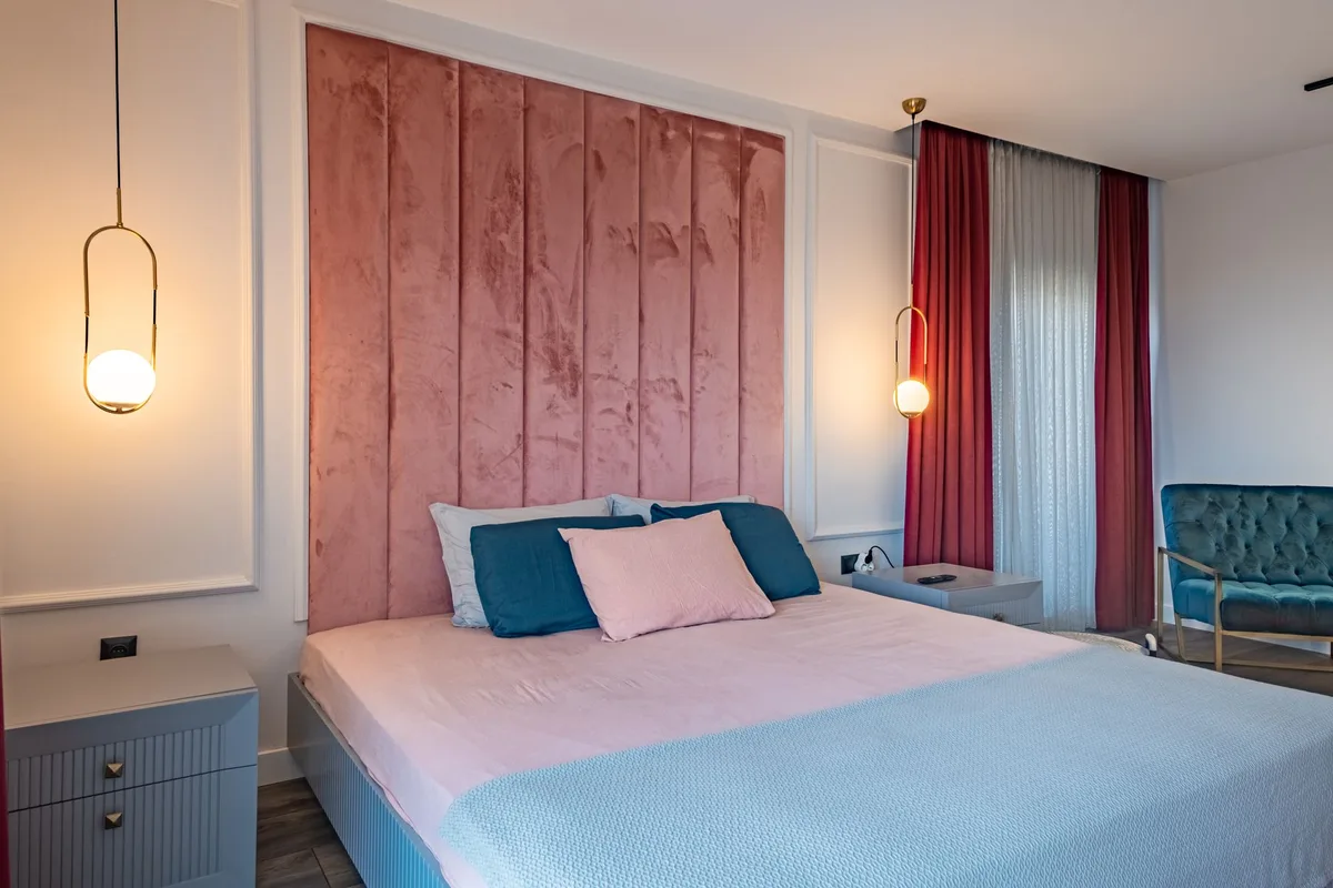 Chambre parentale avec tête de lit matelassée en velours, tonalités chaudes et rangement discret