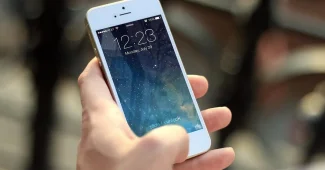 Main d'une personne tenant un téléphone affichant des notifications de paiements récurrents et des icônes d'abonnements
