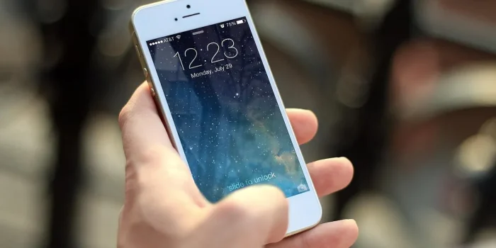 Main d'une personne tenant un téléphone affichant des notifications de paiements récurrents et des icônes d'abonnements