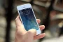 Main d'une personne tenant un téléphone affichant des notifications de paiements récurrents et des icônes d'abonnements