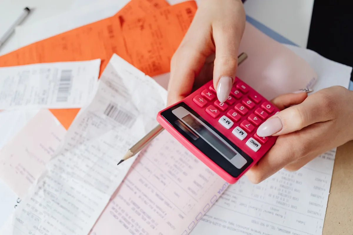 Personne calculant le coût réel de l'énergie avec facture et calculatrice