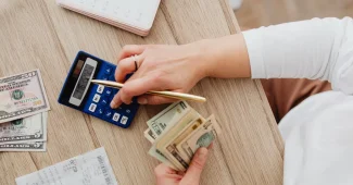 Facture d'électricité et calculatrice sur un bureau, mains tenant le document pour vérifier les coûts