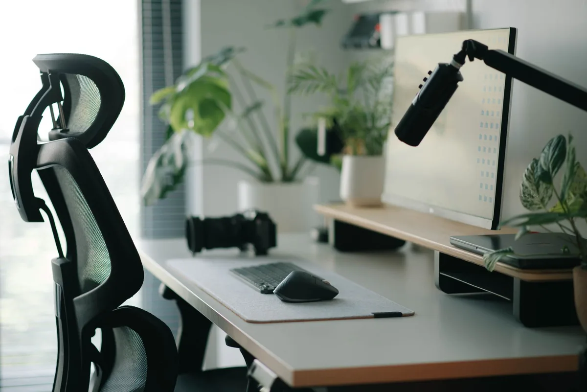 Vue d'une personne assise à un bureau avec une chaise ergonomique, écran à hauteur des yeux, posture correcte