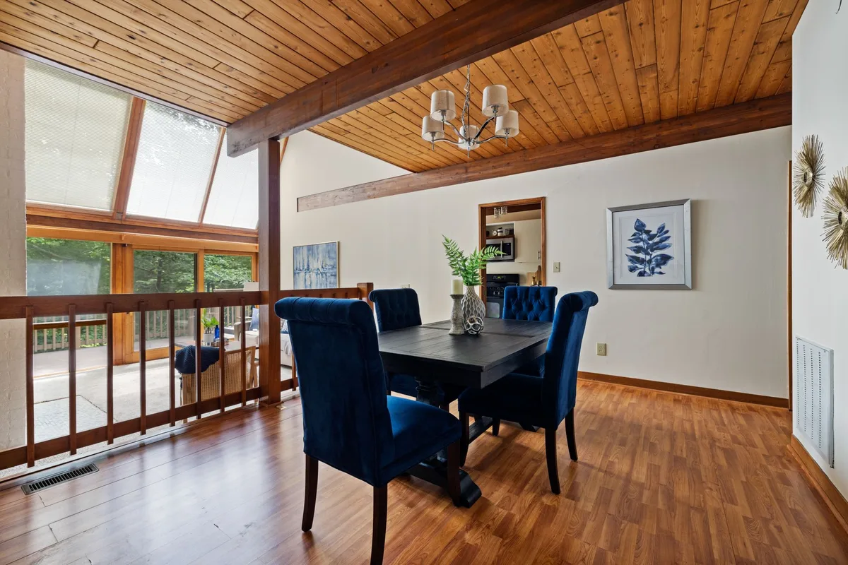 Salle à manger à double hauteur avec immense verrière zénithale diffusant la lumière naturelle