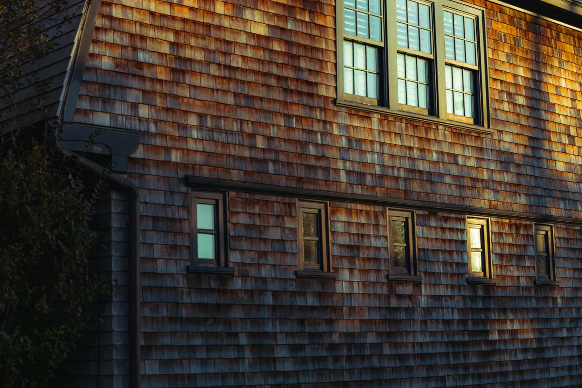 Façade restaurée du cottage avec bardage en cèdre et ouvertures cintrées d'époque