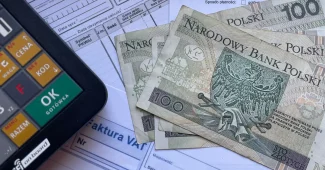 Main d'une personne examinant une facture d'électricité avec une calculatrice sur un bureau