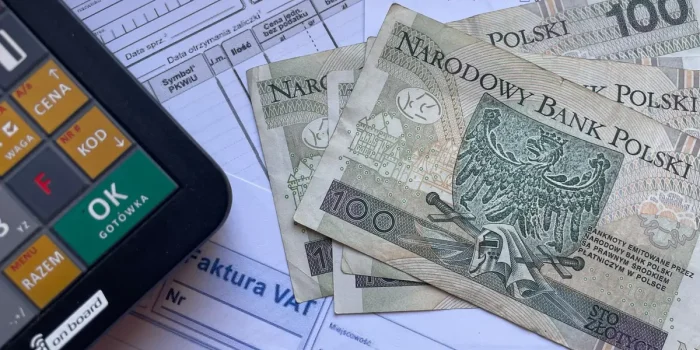 Main d'une personne examinant une facture d'électricité avec une calculatrice sur un bureau