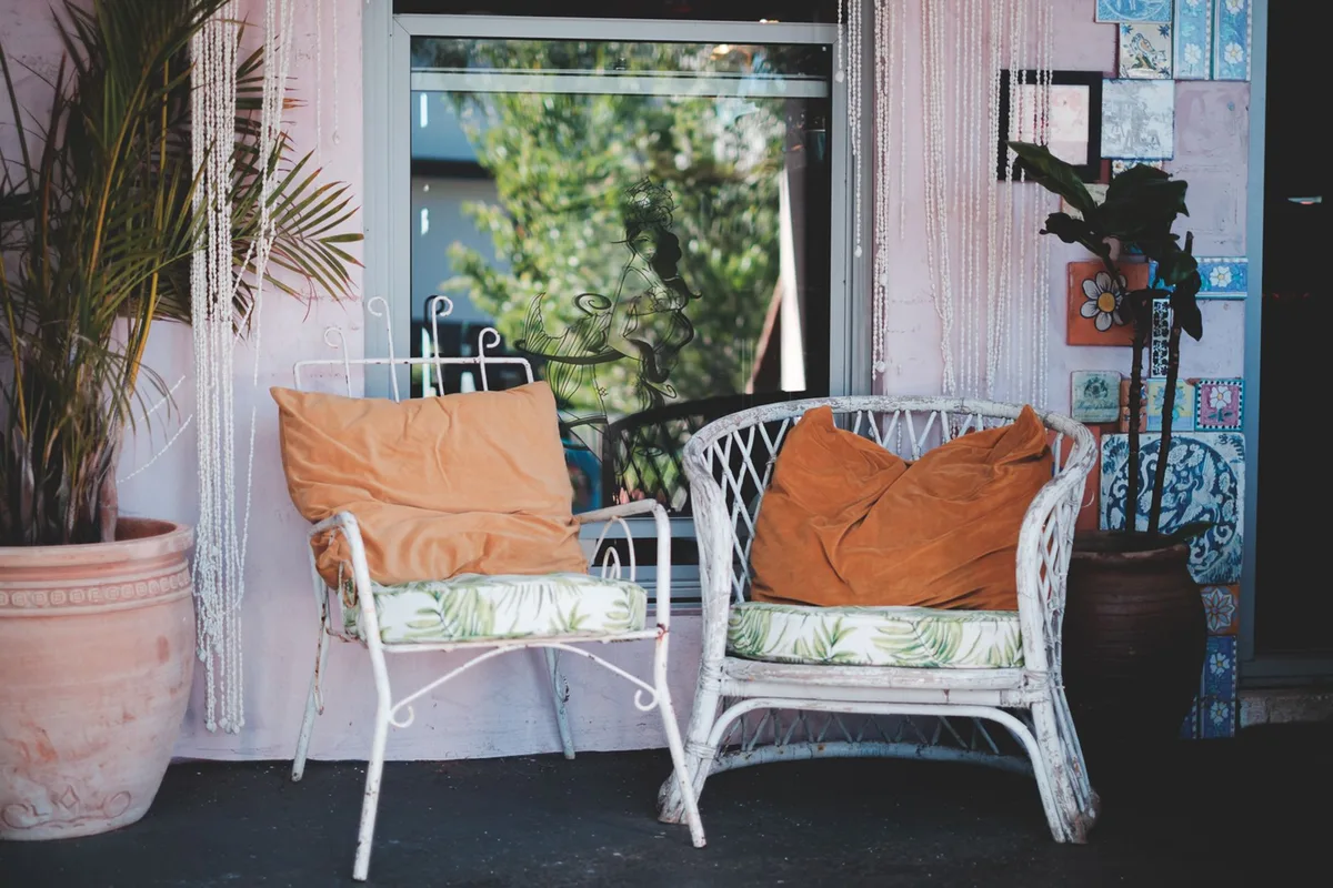 Terrasse bohème avec coussins superposés, plantes volumineuses et assises basses