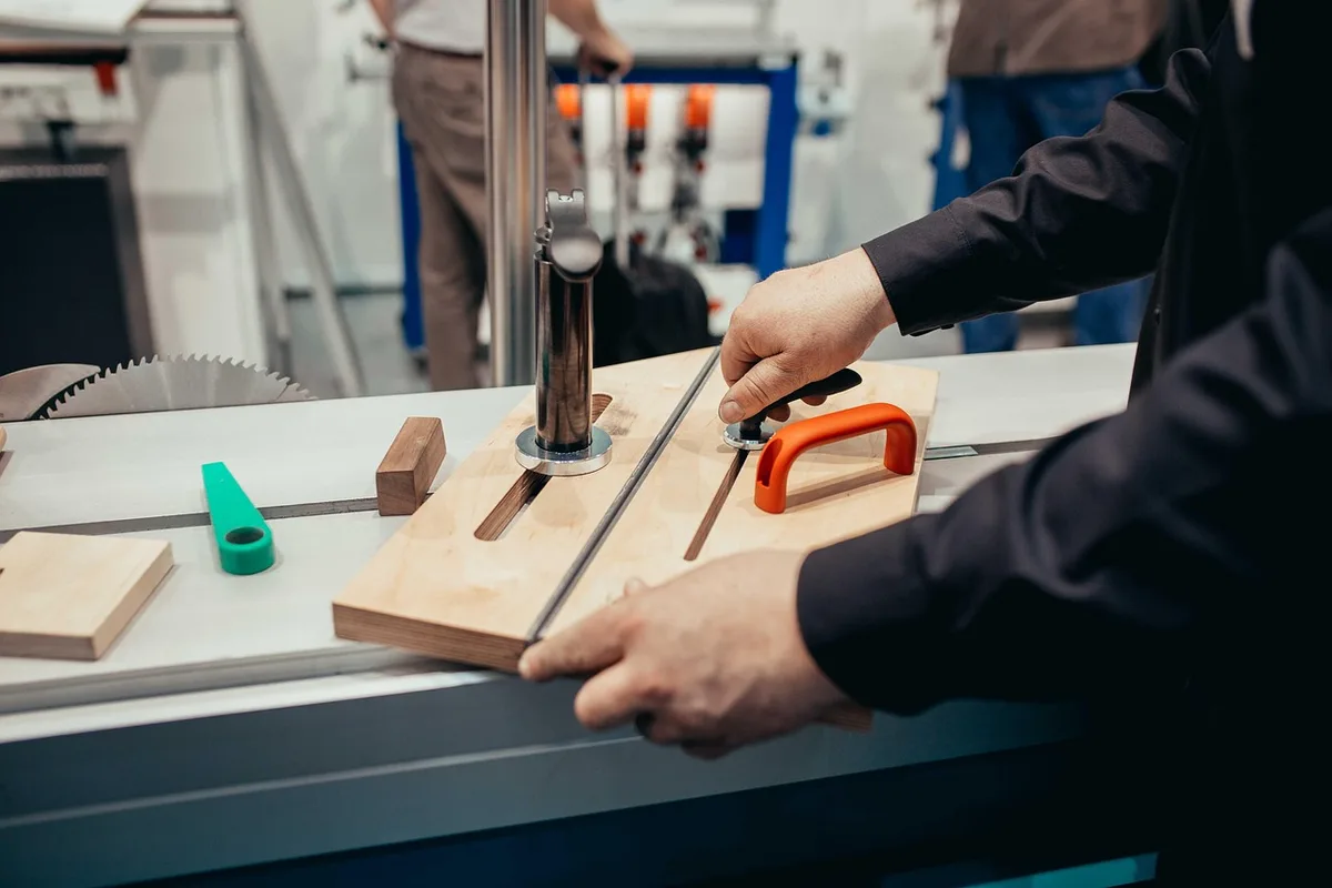 Designer et artisan travaillant autour d'une maquette et d'outils d'ébénisterie en atelier lumineux