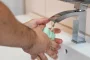 Mains gantées nettoyant un siphon d'évier avec outils posés à côté