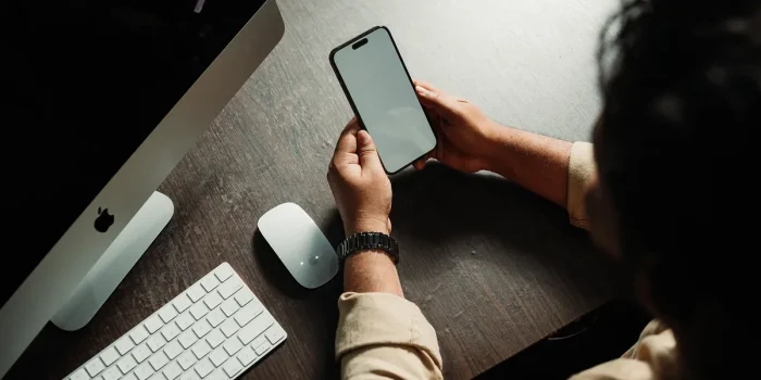 Mains tenant un smartphone affichant l'interface d'un réseau social avec des symboles d'engagement