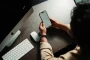 Mains tenant un smartphone affichant l'interface d'un réseau social avec des symboles d'engagement