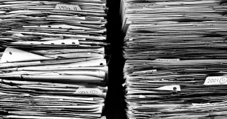 Personne anonyme remplissant un dossier d'aide sur un bureau lumineux près d'une fenêtre