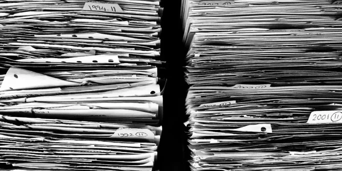 Personne anonyme remplissant un dossier d'aide sur un bureau lumineux près d'une fenêtre
