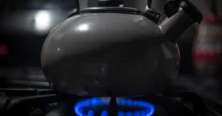Main de cuisiner actionnant le brûleur d'une cuisinière à gaz dans une cuisine moderne
