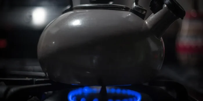 Main de cuisiner actionnant le brûleur d'une cuisinière à gaz dans une cuisine moderne