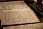 Personne recherchant la signification d'un acronyme sur un ordinateur avec des documents papier et une loupe