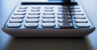Mains tenant une facture d'électricité imprimée avec calculatrice sur un bureau