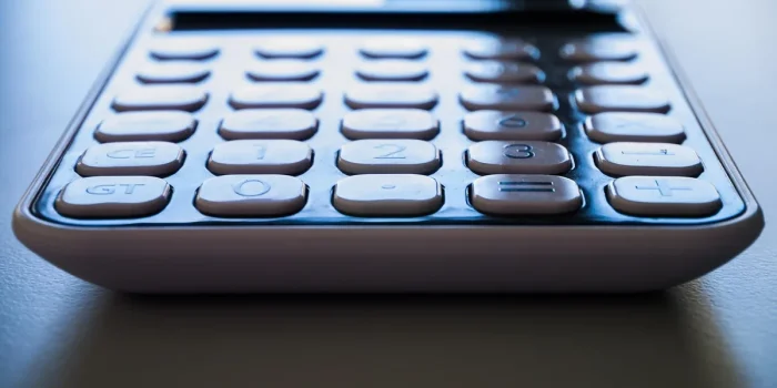 Mains tenant une facture d'électricité imprimée avec calculatrice sur un bureau