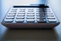 Mains tenant une facture d'électricité imprimée avec calculatrice sur un bureau