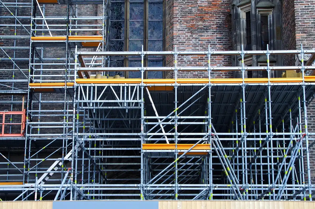 Chantier intérieur en journée avec artisans anonymes et plans posés sur une table