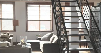 Coin salon lumineux avec canapé, fauteuil et banc près d'une grande fenêtre