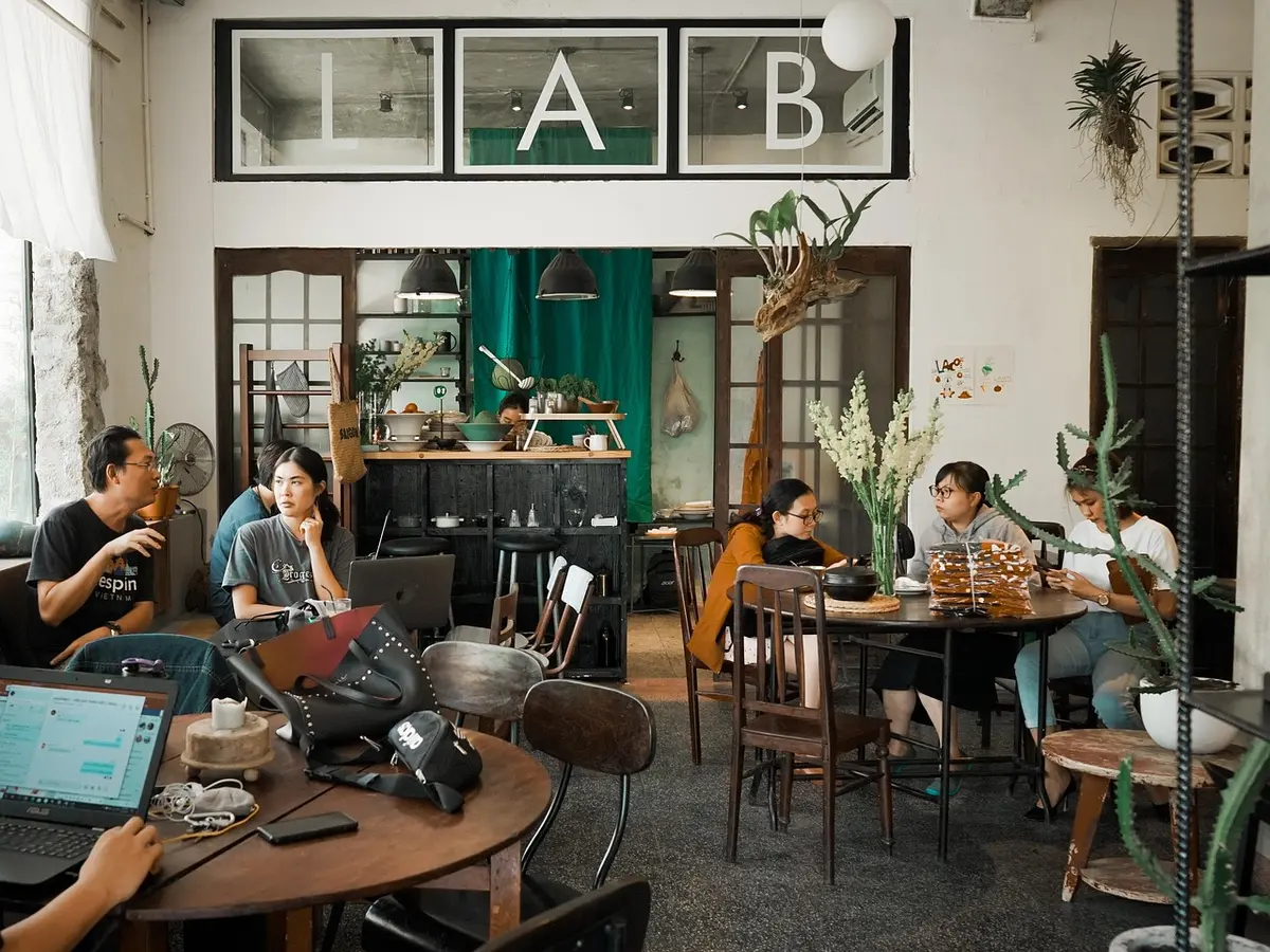 Table de réunion avec plans, photos et mains préparant un rendez‑vous