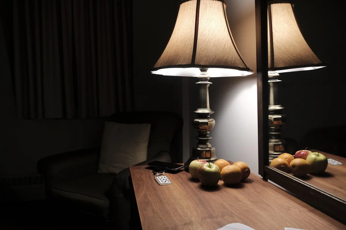 Rideaux occultants ouverts laissant entrer la lumière douce du jour et lampe de chevet