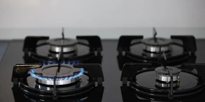 Mains anonymes ajustant un thermostat près d’une chaudière avec une facture de gaz sur la table