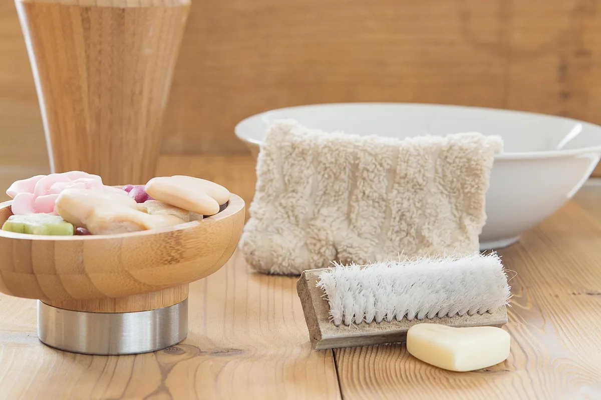 Personne anonyme nettoyant une table en teck avec une brosse et du savon doux