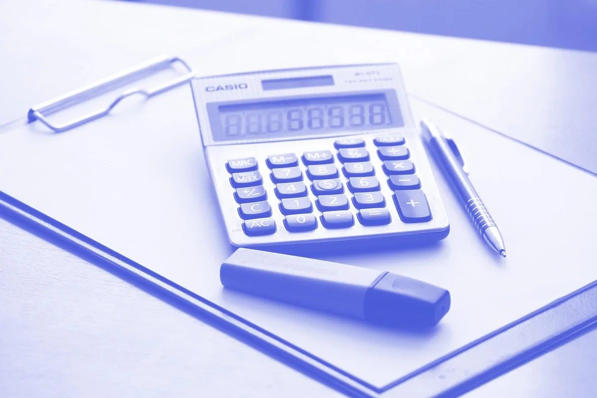 Calculatrice et papiers avec chiffres illustrant un exemple de calcul de taxe